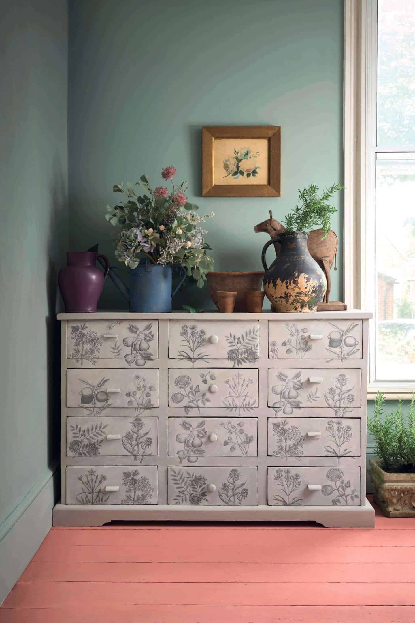 Green room containing decoupage dresser and pink painted floor boards