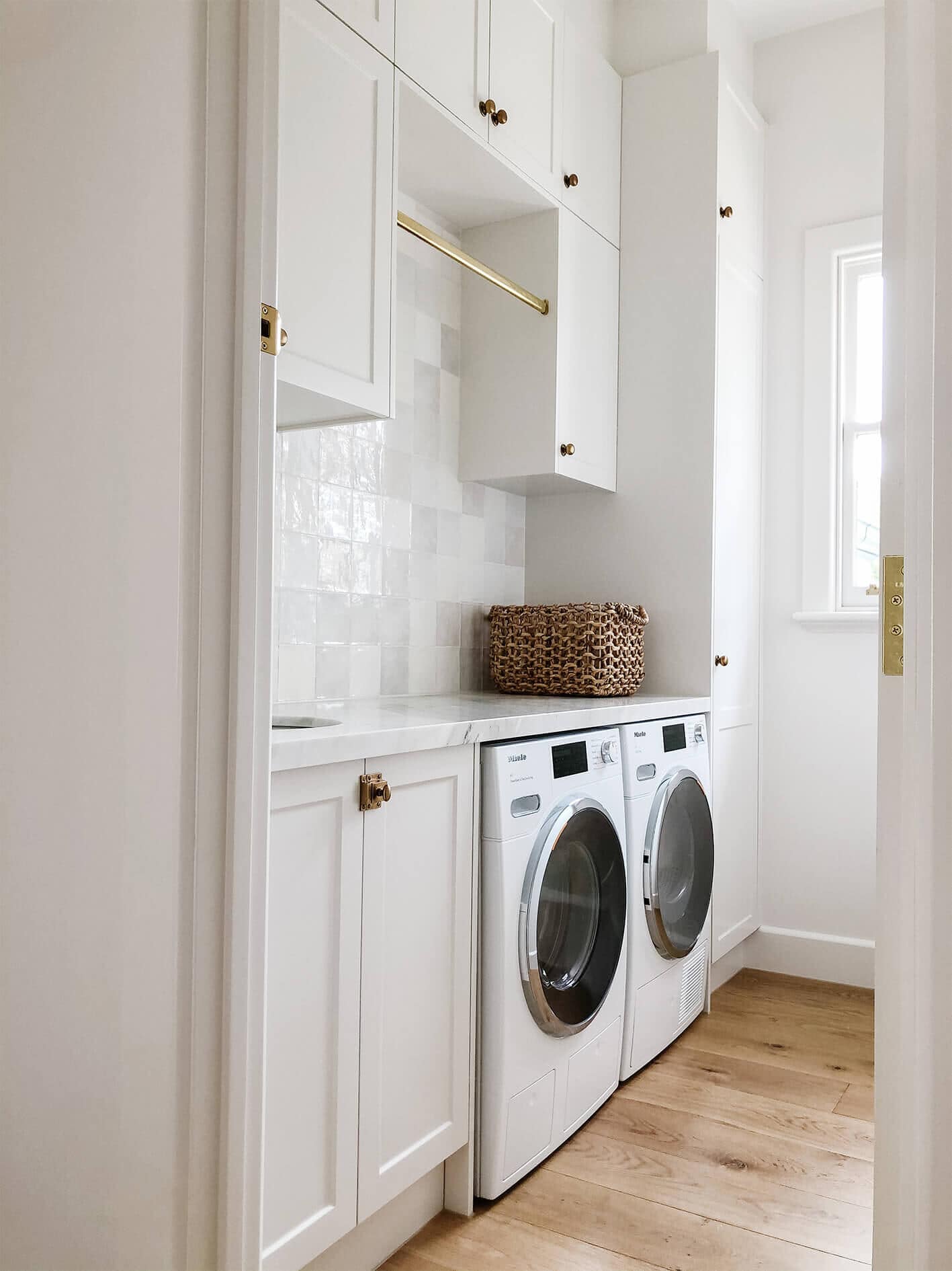 A white utility room with quartz counter and white zellige tiles