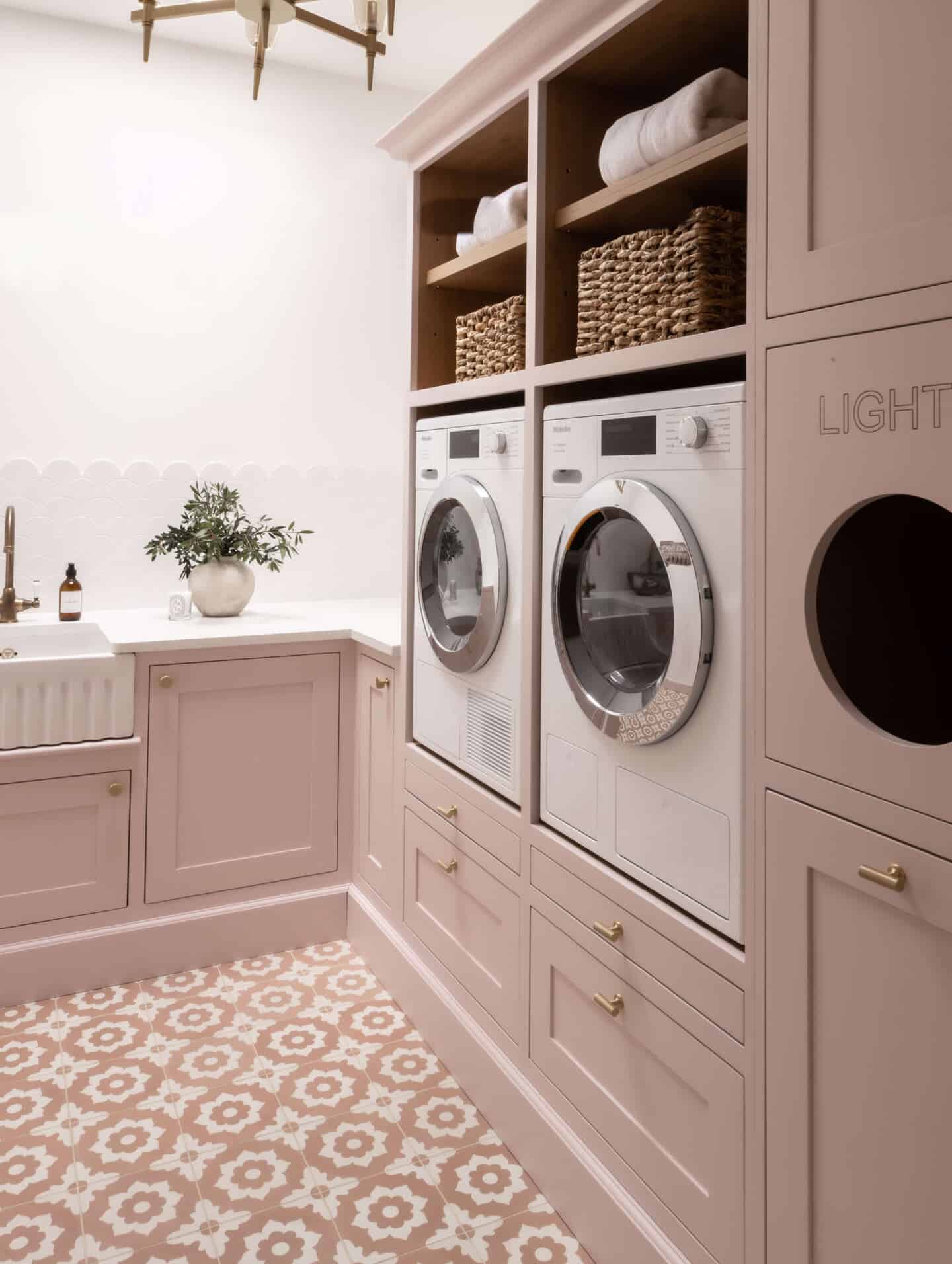 Pink utility room with elevated washing machine and tumble dyer and a Belfast sink