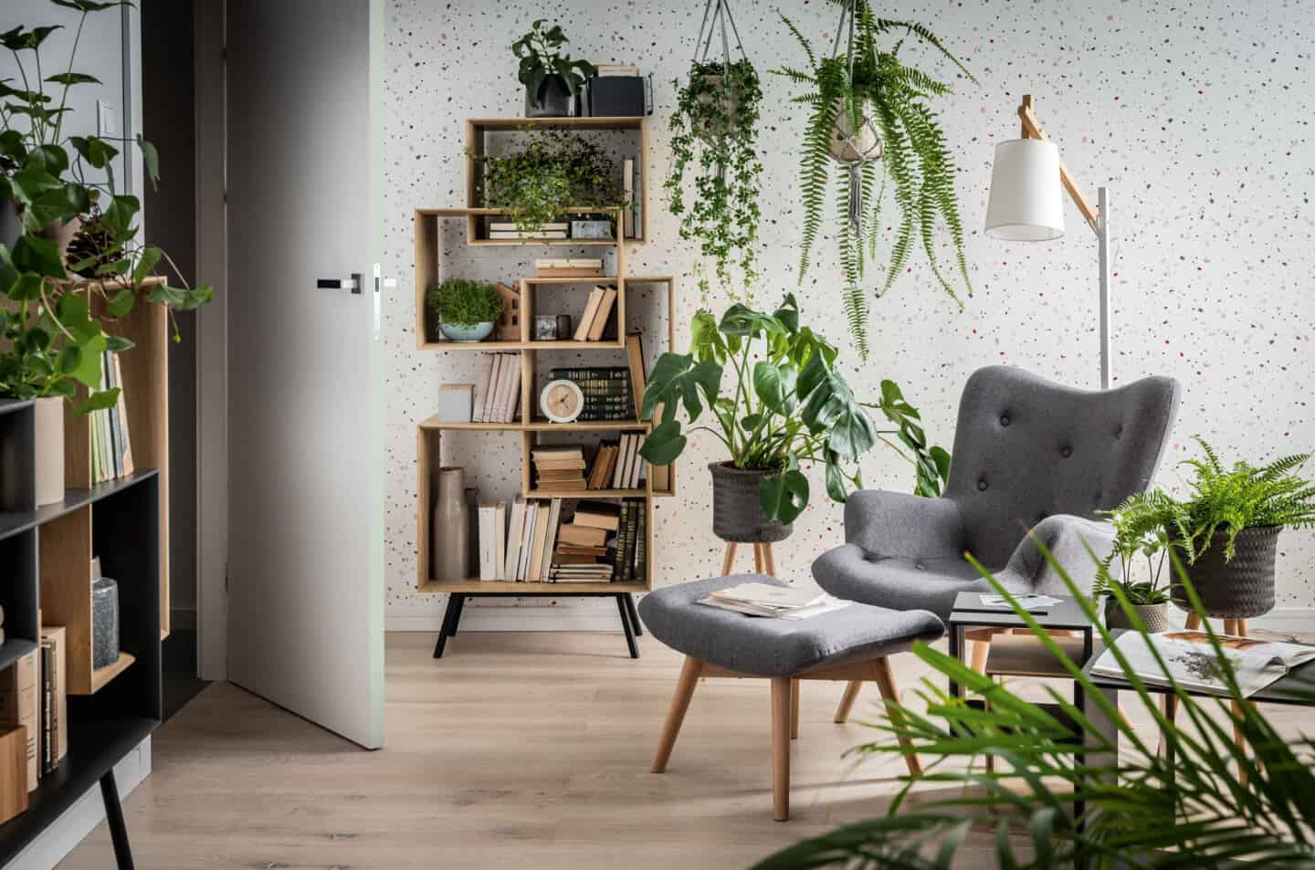 Biophilia in design. Living room and featuring a grey chair and footstool surrounded by plants.