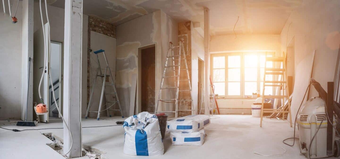A home in the process of renovation with bare walls and floors, hanging cables and lots of step ladders