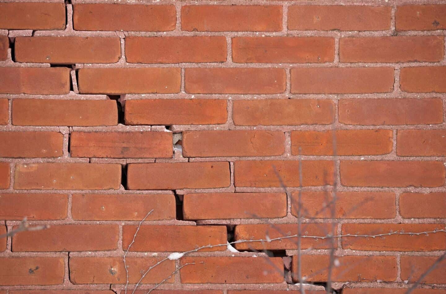 A red brick wall with a large crack down it