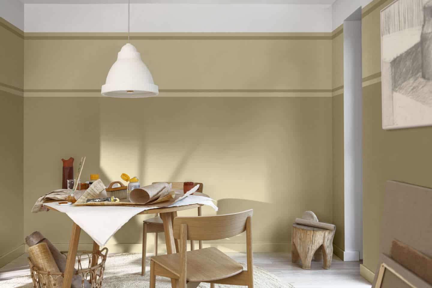 A wooden table covered in craft supplies stands in the middle of a room with yellow painted walls