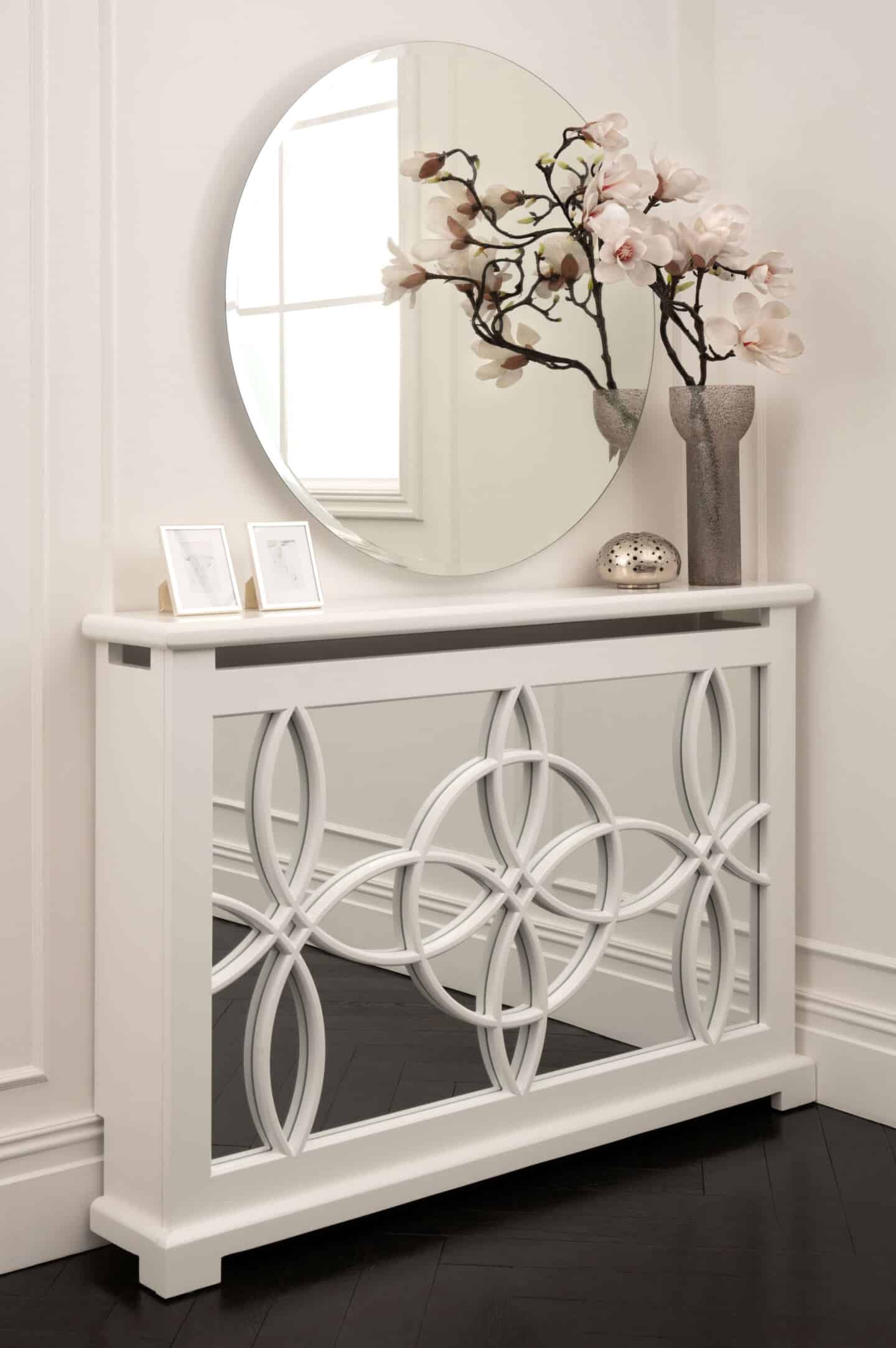 An ornate art deco mirrored radiator cover with white paneled wall behind