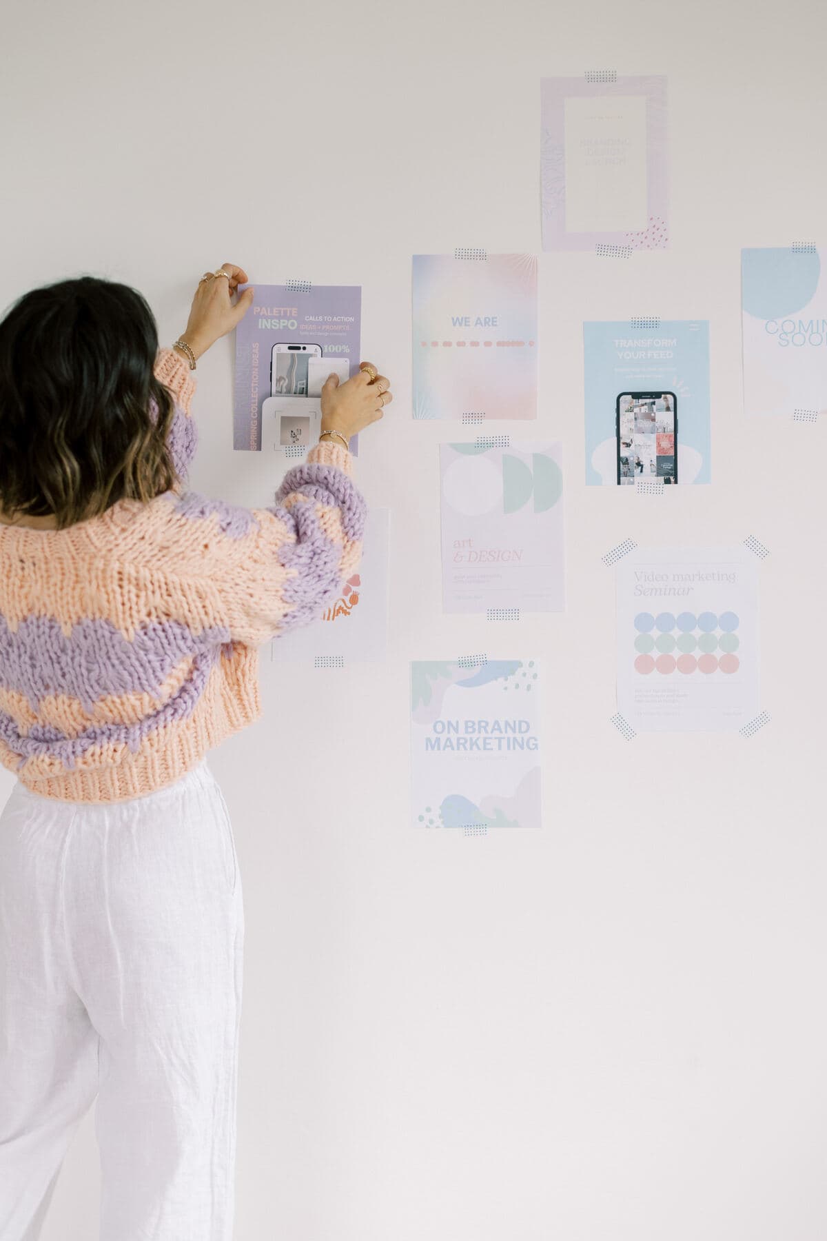 A woman sticking prints on the wall using washi tape