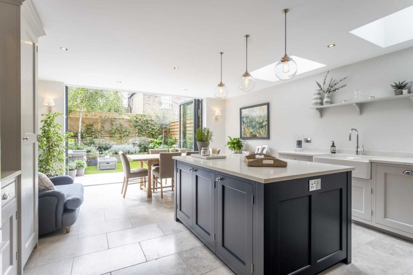 A navy and grey shaker style kitchen with bi-fold doors that open up to the garden