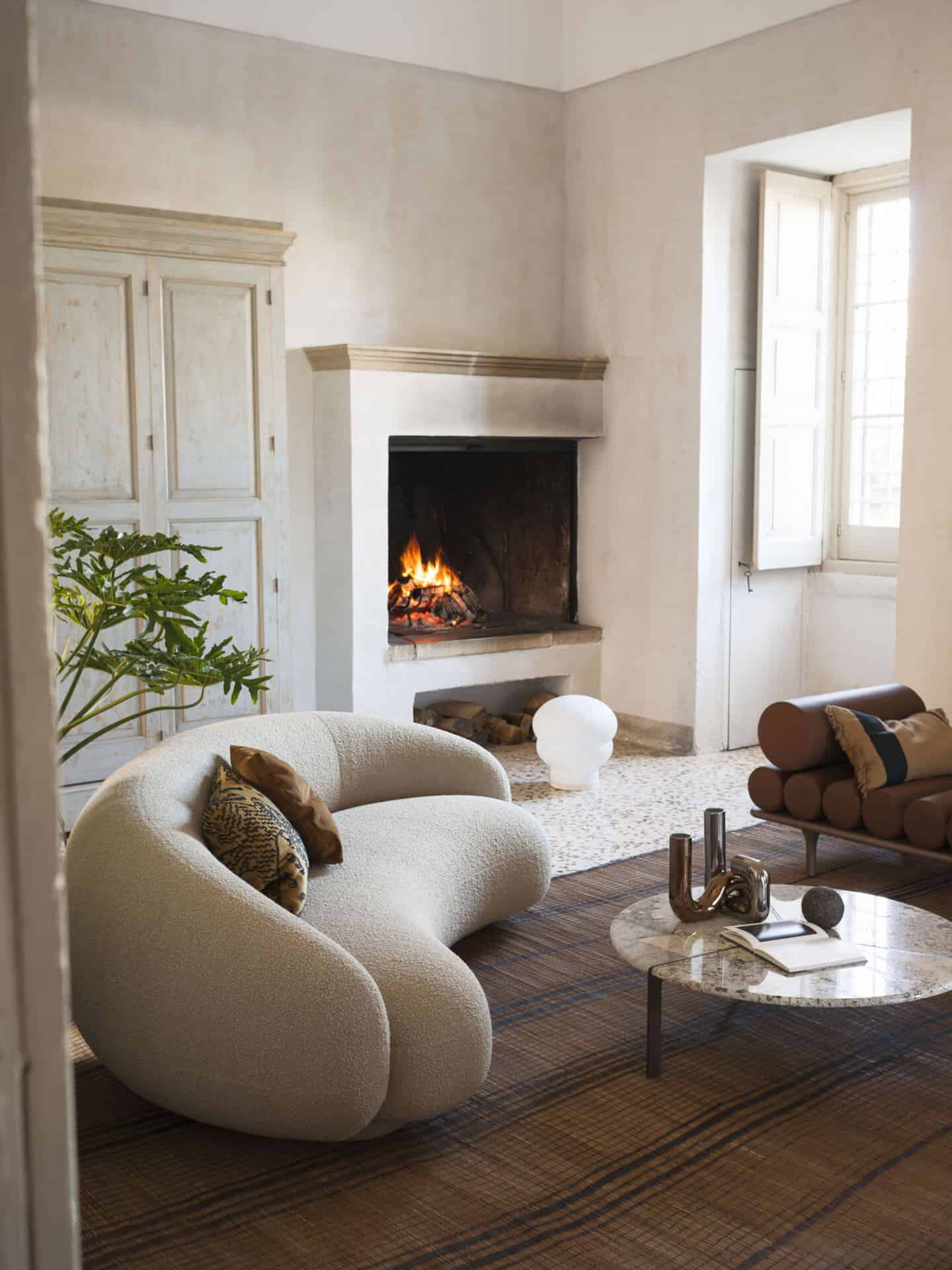 A curved sofa and coffee table in front of a fireplace