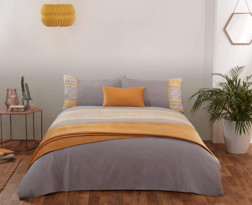 A grey and ochre bedroom with wooden flooring and plants
