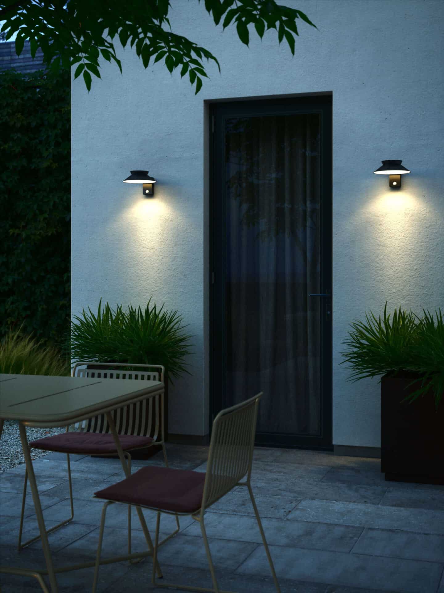 Wall lights mounted besides a black door in a garden