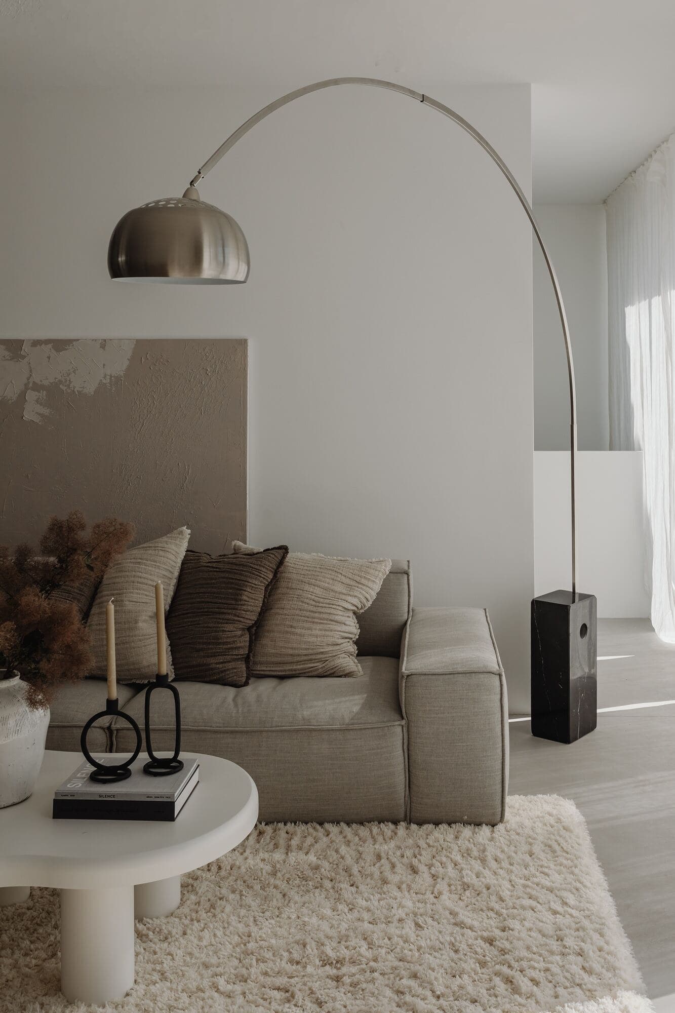 A calming living space featuring a sofa covered in cushions and a large floor lamp