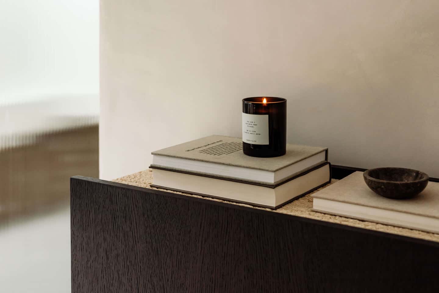 A candle on a pile of books on a sideboard in a calming living space