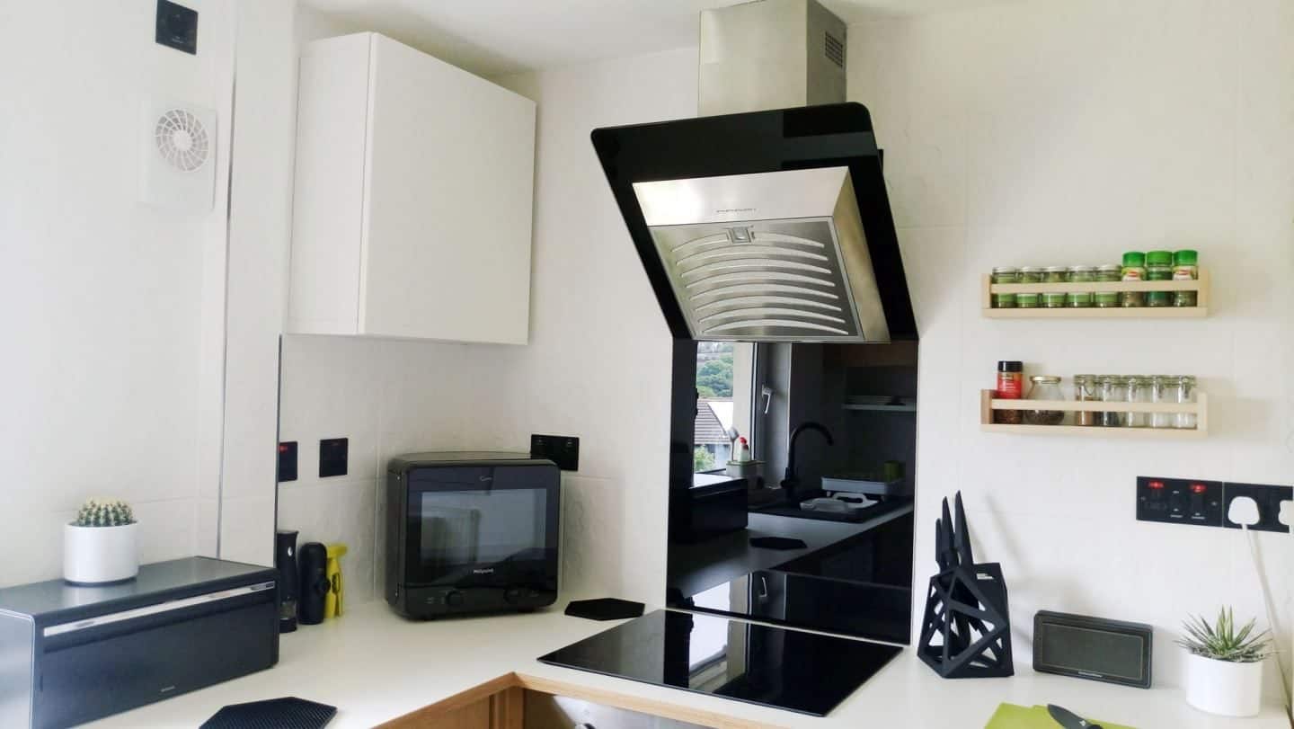 A small white kitchen with black appliances and accessories
