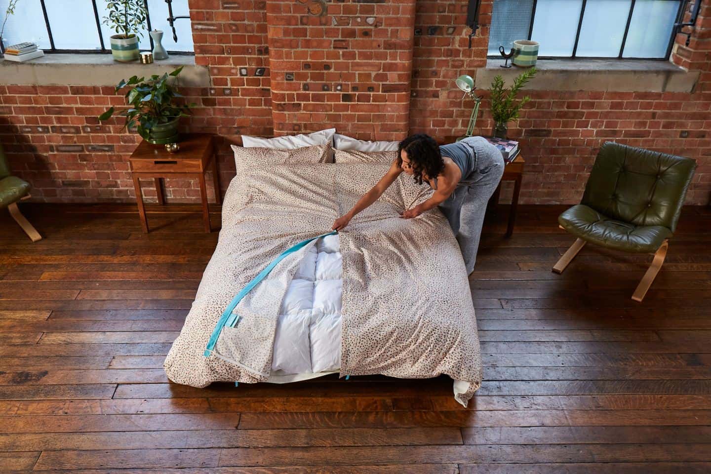 Koa revolutionary duvet cover shown in an industrial loft bedroom. A women zips up the central zip. The easy way to change a duvet cover