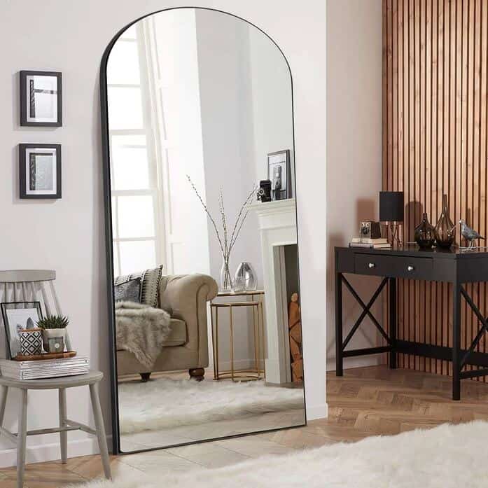 Large floor standing arched mirror in a living room placed strategically opposite a window to bounce light around