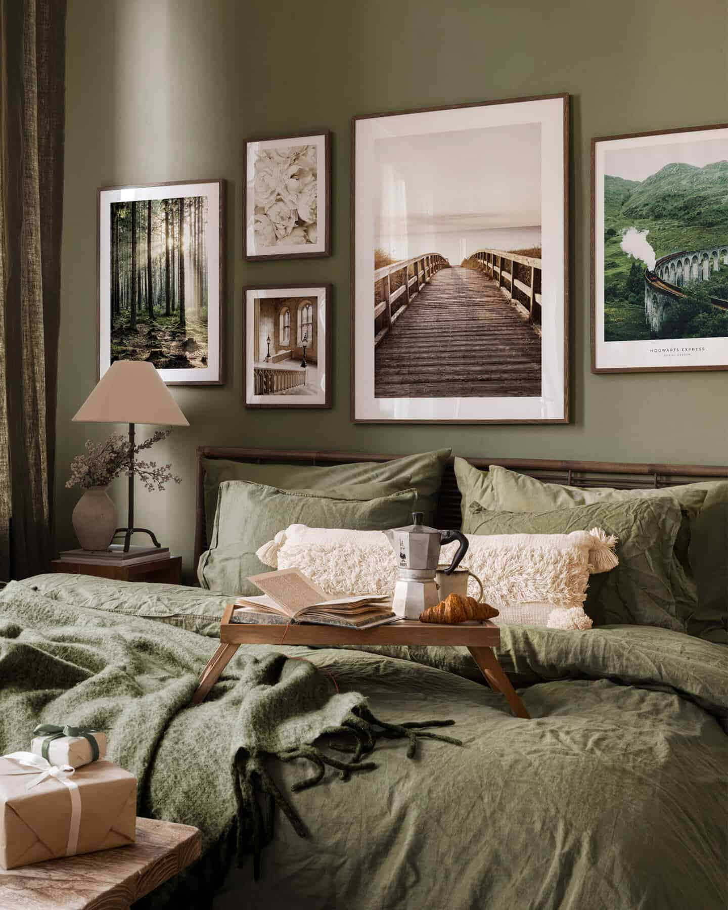 A gallery wall of nature images behind a bed made with green linen bedding