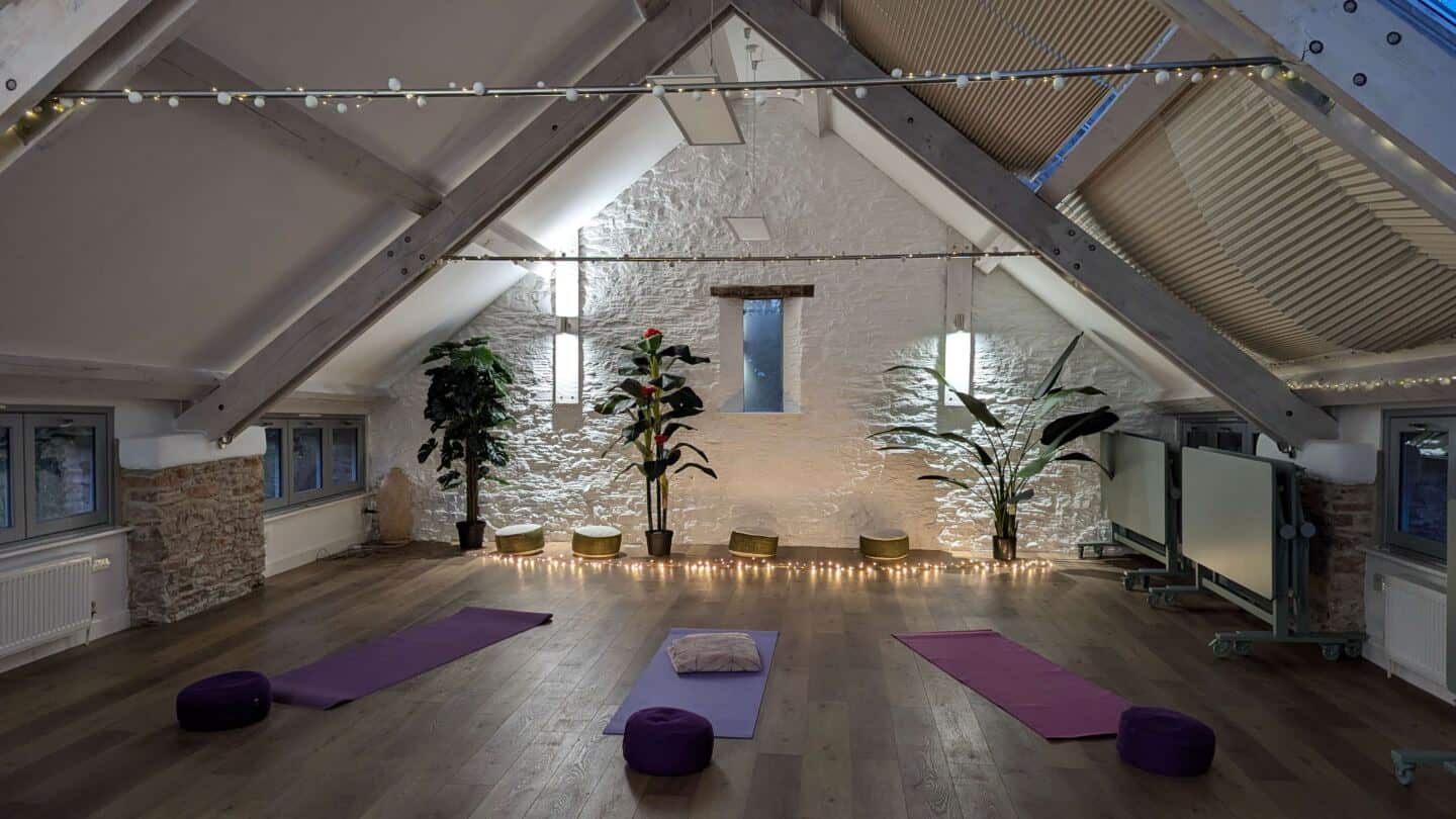 An evening yoga session in a studio with vaulted ceilings. Twinkly fairy lights on the floor