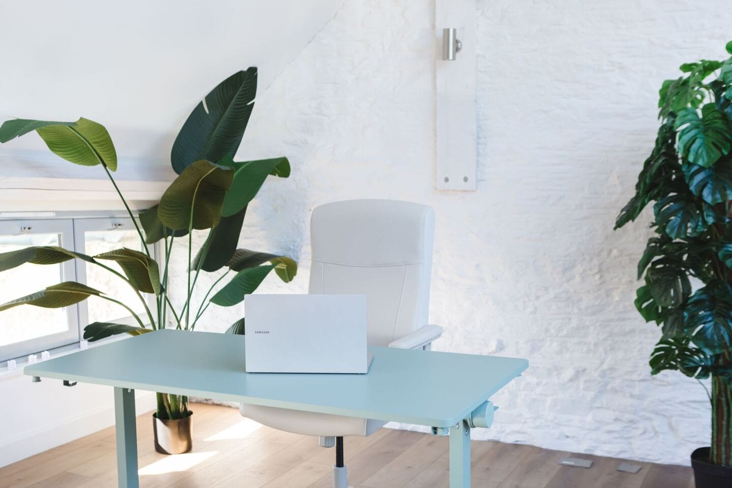 A desk and chair next to artificial plants from Blooming Artificial in an office