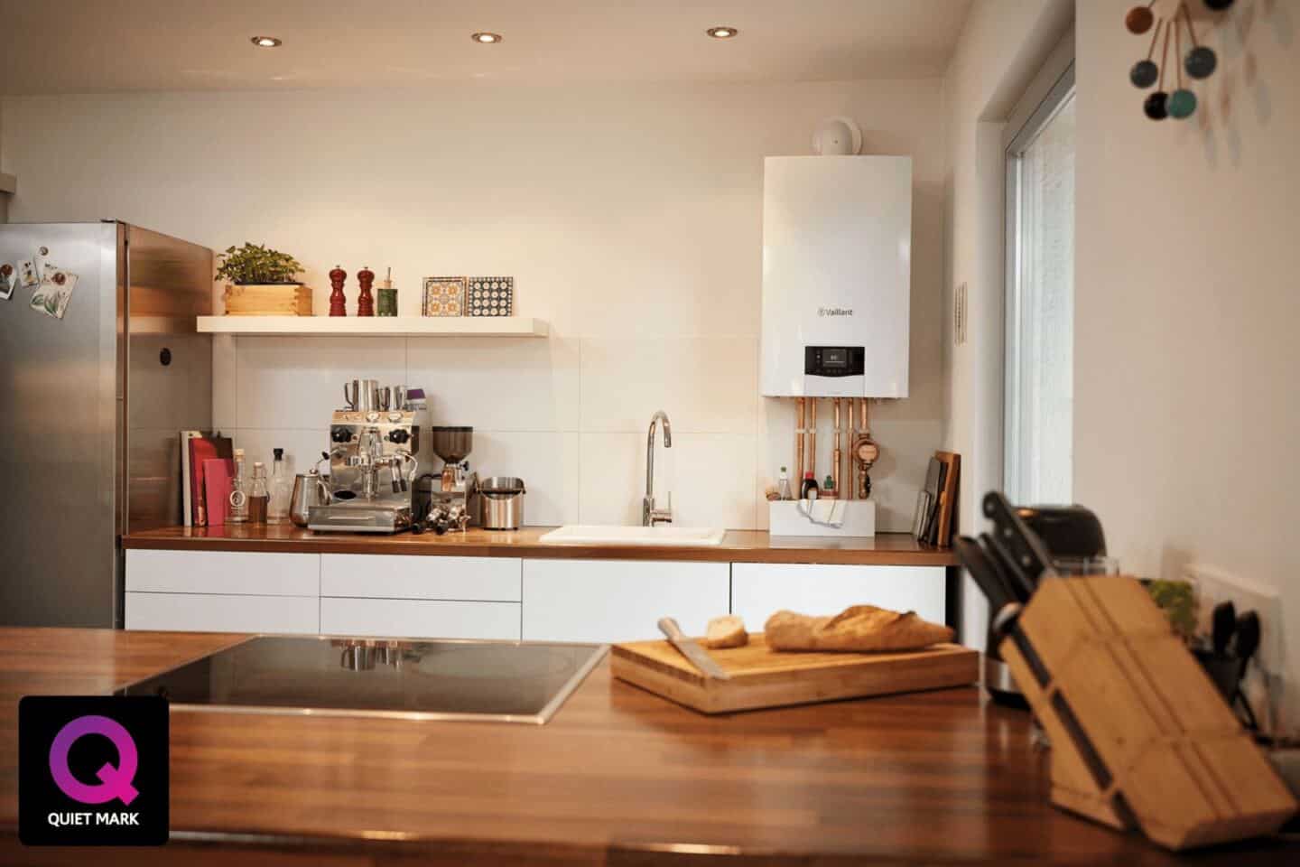 A modern white kitchen featuring a wall mounted boiler
